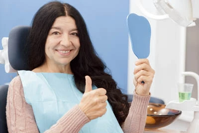 woman looking in the mirror at her restored smile