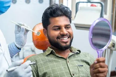 man looking in a mirror at the dentist