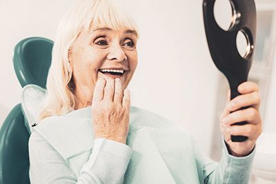 woman looking in the mirror at her freshly cleaned smile